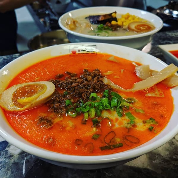 Two bowls of ramen, one with a spicy red broth, egg, ground meat, and green onions.