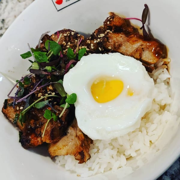 Itto Ramen Bar's rice bowl with grilled pork, a fried egg, and microgreens.