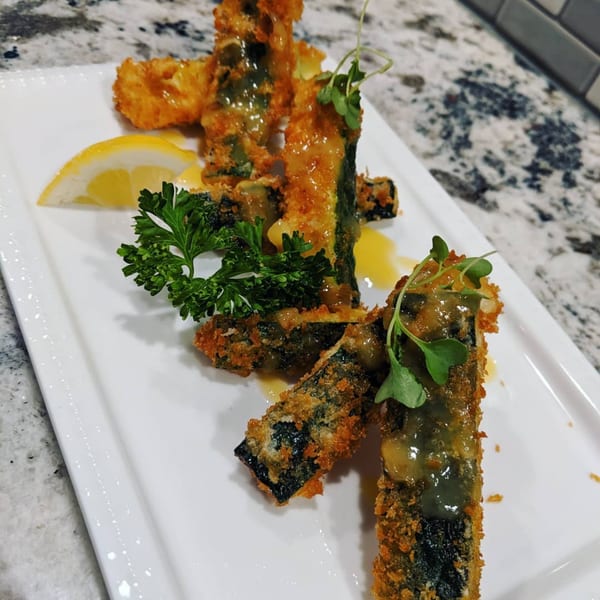 Crispy fried seaweed tempura drizzled with sauce, garnished with parsley and a lemon wedge.