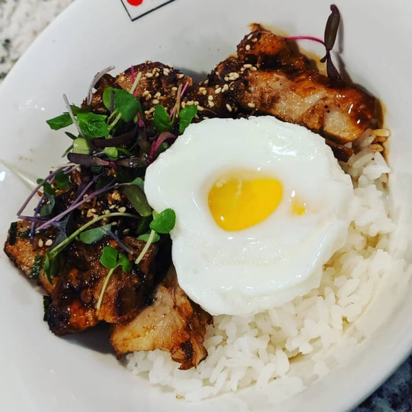 Itto Ramen Bar's Japanese tapas dish with rice, glazed pork, microgreens, and a sunny-side-up egg.